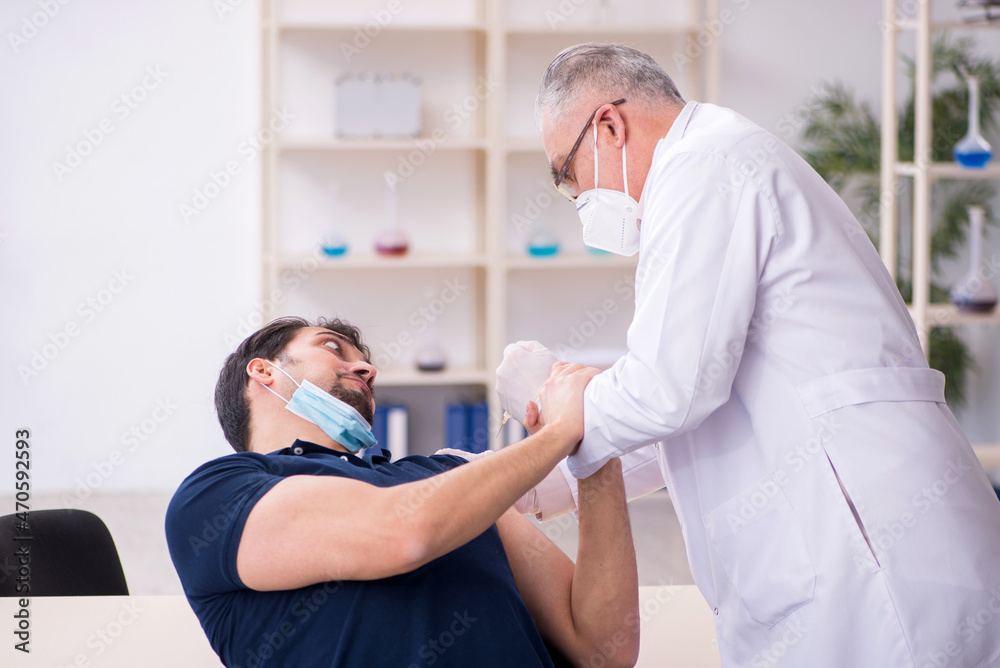 Obraz premium Young male patient visiting old male doctor in vaccination conce
