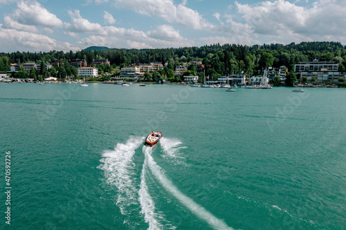 Austria, Carinthia, Velden am Worther See, Aerial view of motorboat leaving wake across turquoise waters of Worthersee lake photo