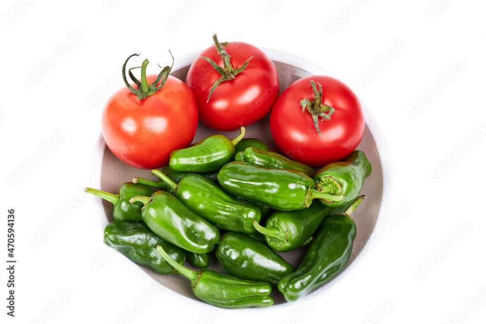 Green peppers and red tomatoes on a plate on a white background. Vegetarian food concept Green peppers and red tomatoes on a plate on a white background. Vegetarian food concept