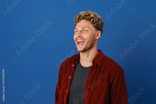 Young blonde man with curly hair laughing and looking aside