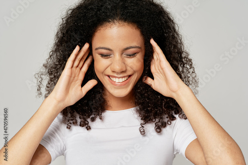 cheerful woman with curly hair holding her head close-up