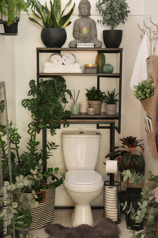 Stylish restroom interior with toilet bowl and green houseplants