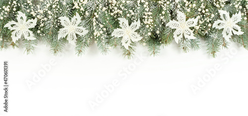 Christmas banner with pearl beads and glitter flowers on a white background with copy space. The snow-covered spruce branches are decorated with white flowers and a pearl garland.