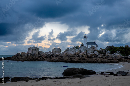 Phare de Bretagne sur une jolie plage au lever du soleil sous un ciel chargé de nuages gris