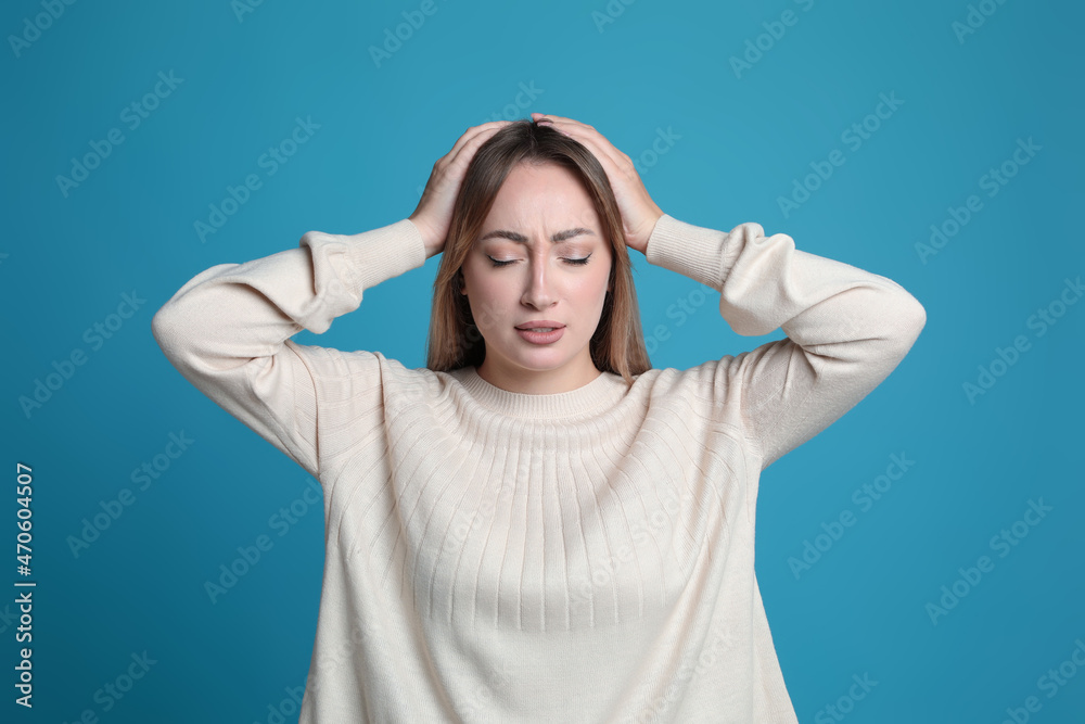 Young woman suffering from headache on light blue background Young woman suffering from headache on light blue background