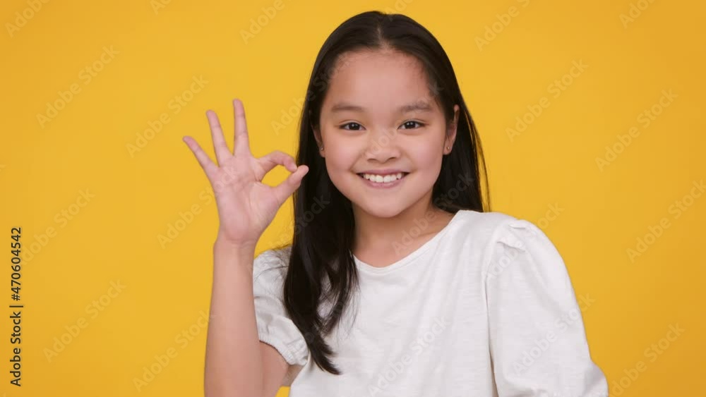 Approval and enjoyment. Happy confident preteen asian girl showing okay gesture and smiling to camera Approval and enjoyment. Happy confident preteen asian girl showing okay gesture and smiling to camera