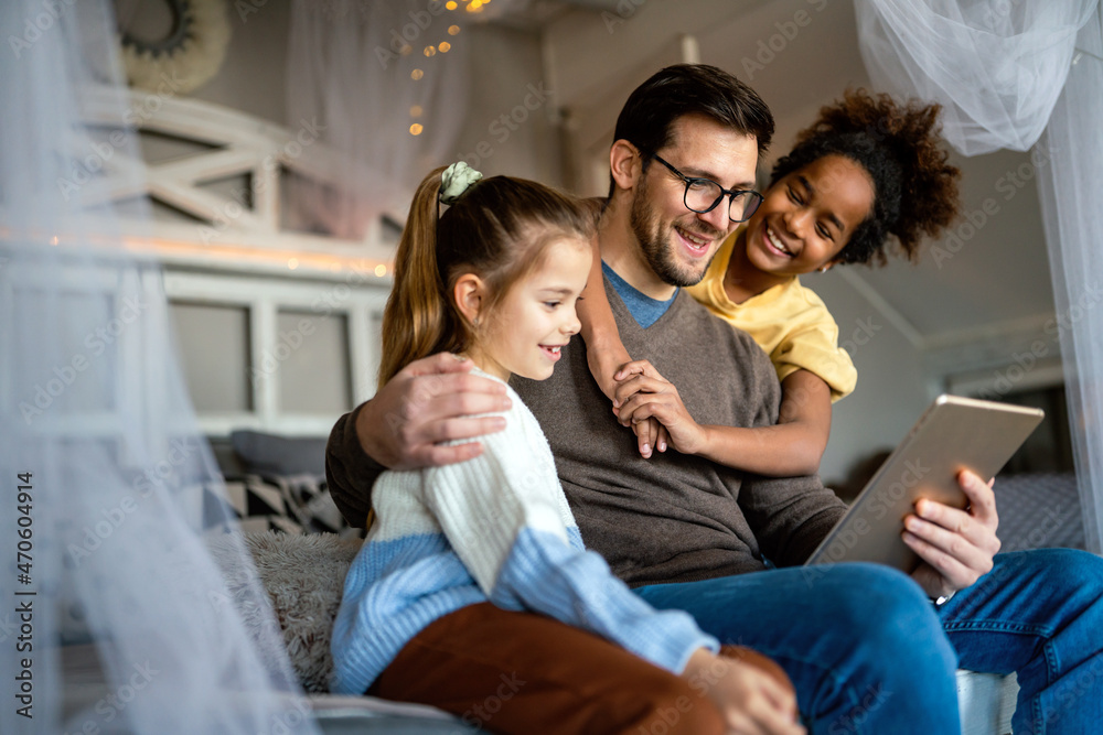 Multiethnic children and father having fun, playing on tablet at home Multiethnic children and father having fun, playing on tablet at home