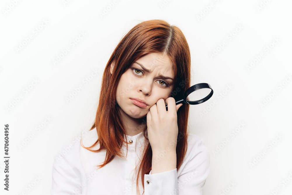 red-haired woman in a white shirt with a magnifying glass in her hands searching red-haired woman in a white shirt with a magnifying glass in her hands searching