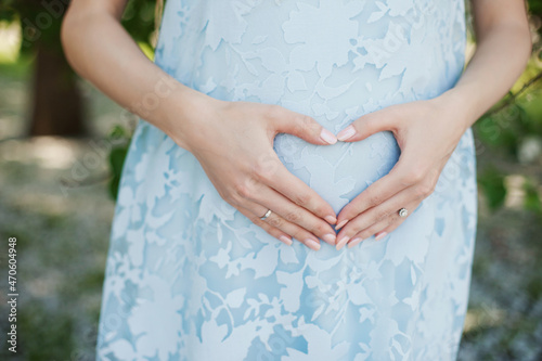 woman holding her hands on pregnant belly as a heart. Hands in heart shape on a belly of pregnant woman. photo