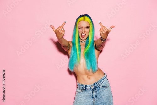 Shirtless woman with multicolored hair showing middle fingers