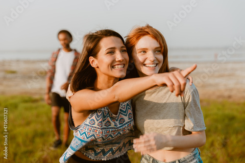 Young white women hugging and pointing finger aside outdoors