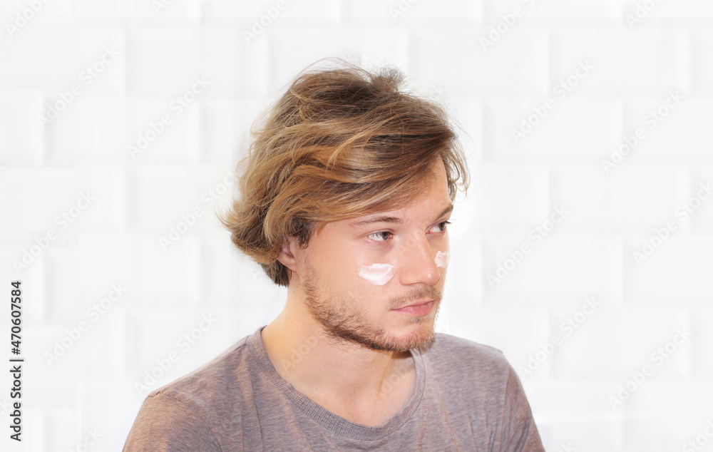 young man taking care of his undereye wrinkles applying facial mask. Applying the cream young man taking care of his undereye wrinkles applying facial mask. Applying the cream