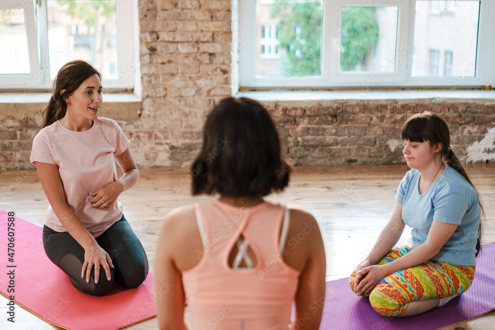 Young woman with down syndrome having yoga class with coach indoors Young woman with down syndrome having yoga class with coach indoors