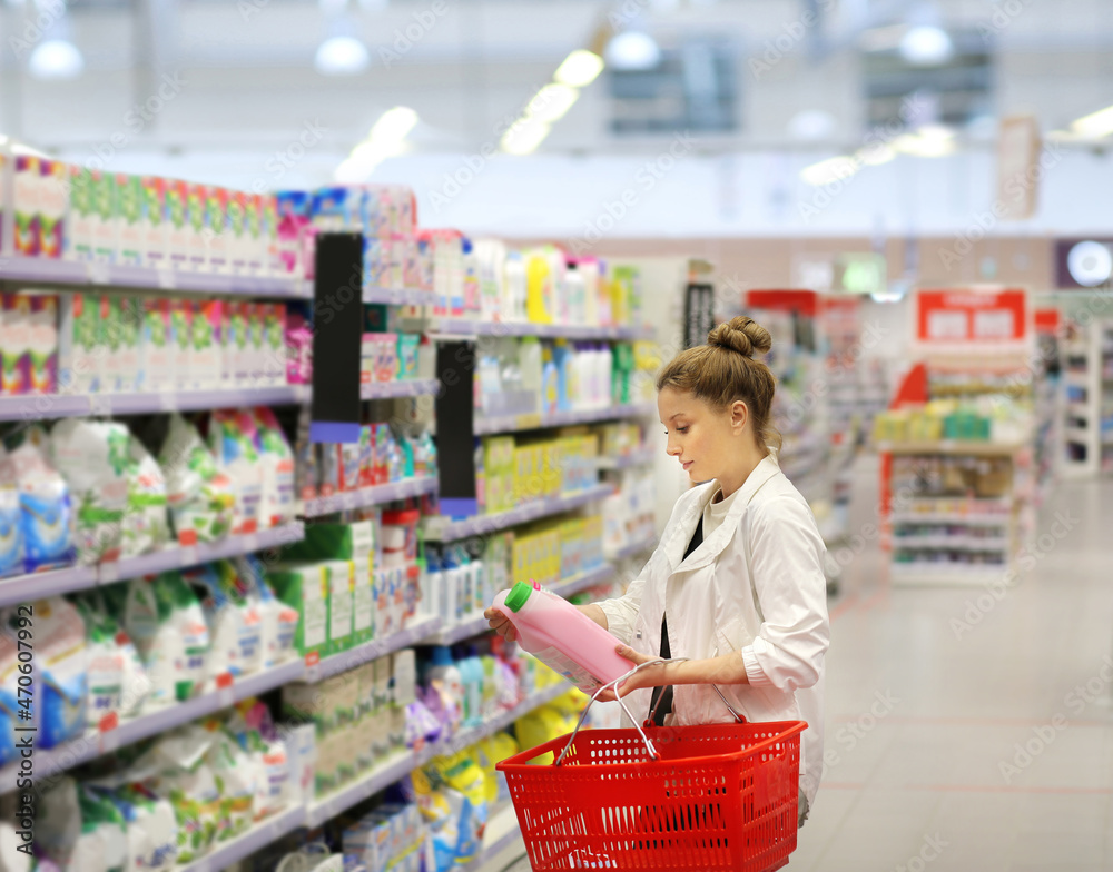 Woman shopping in supermarket reading product information.woman choosing laundry detergent in supermarket