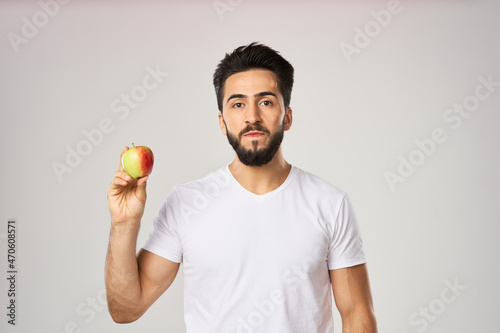 Cheerful man in a white t-shirt with an apple in the hands of health fruits