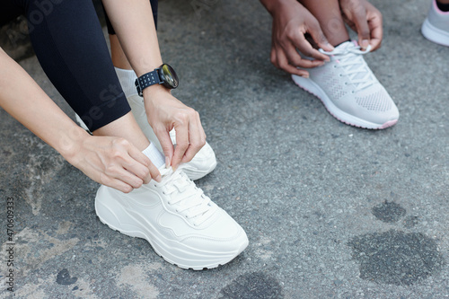 Cropped image of young women tying shoelaces when getting ready for morning run outdoors photo