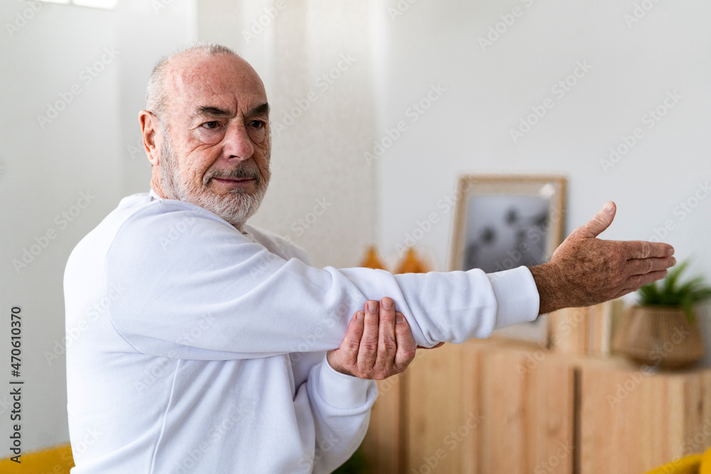Fit senior man doing warm up exercise at home Fit senior man doing warm up exercise at home
