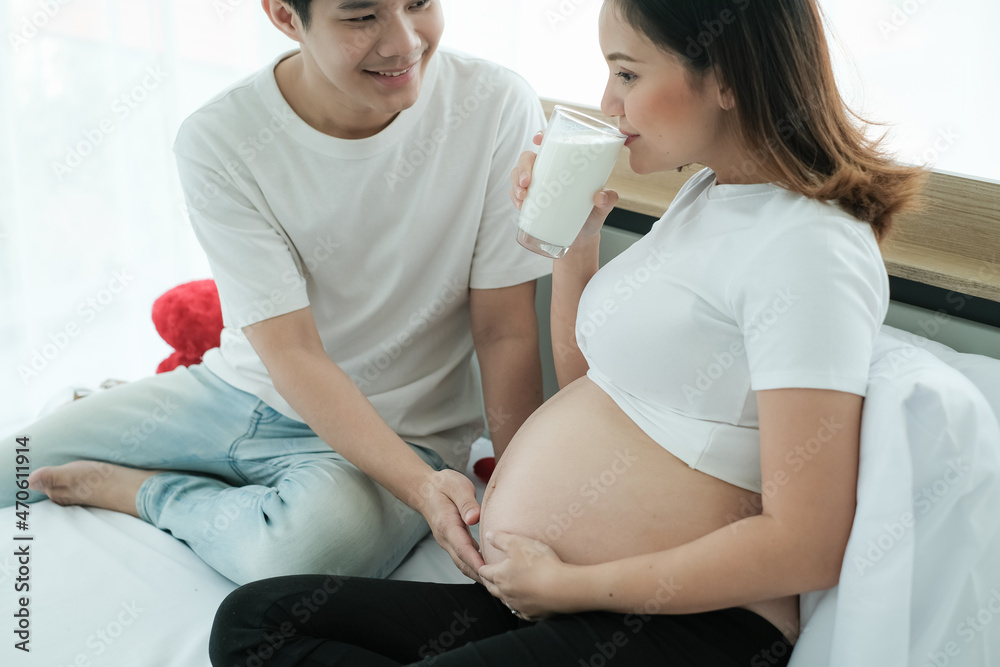 Fototapeta premium Asian man take care pregnant woman and drinking milk