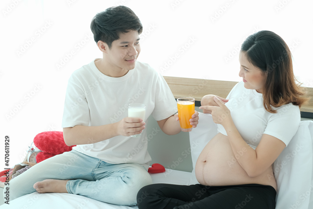 Asian man take care pregnant woman and drinking milk Asian man take care pregnant woman and drinking milk