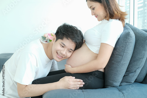 portrait asia young pregnant woman and husband happy together on sofa