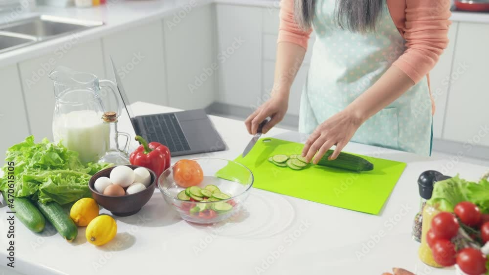 Middle aged lady have party do vegan veggie lunch cut zucchini in kitchen Middle aged lady have party do vegan veggie lunch cut zucchini in kitchen