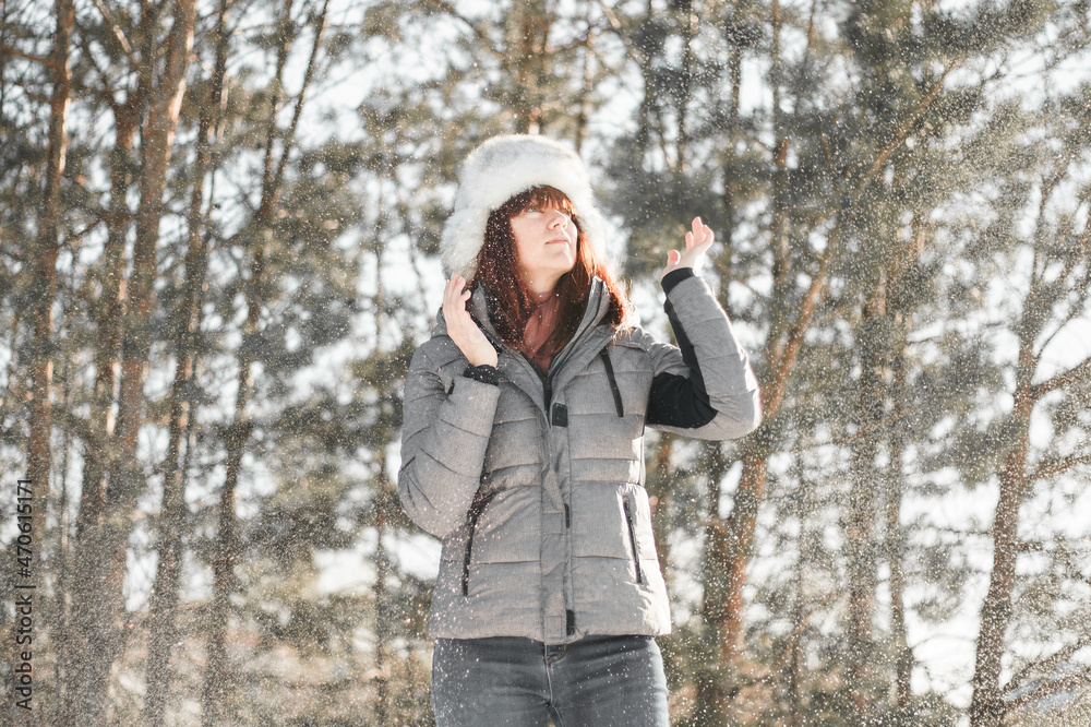 Winter fun. Woman plays throwing snow with arms up open in freedom enjoying cold season. Happy and joyful concept.