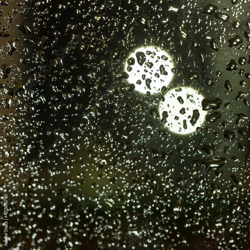 colorful diffuse unsharp lights behind glass window with rain drops