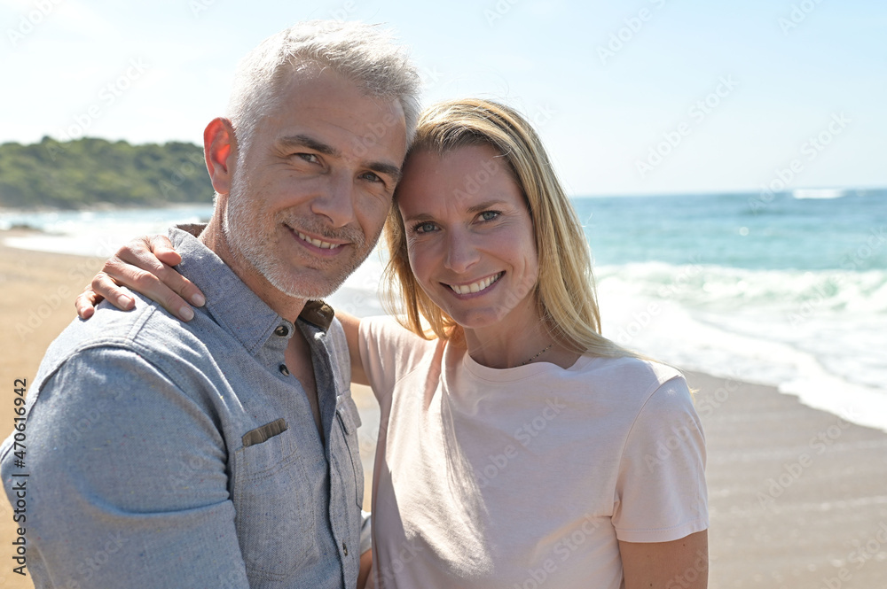 Middle-aged couple walking on a sandy beach Middle-aged couple walking on a sandy beach