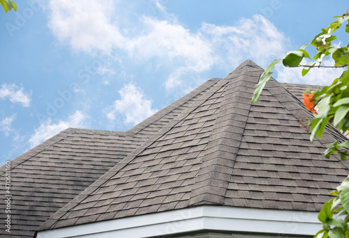 edge of Roof shingles on top of the house, dark asphalt tiles on the roof background. photo