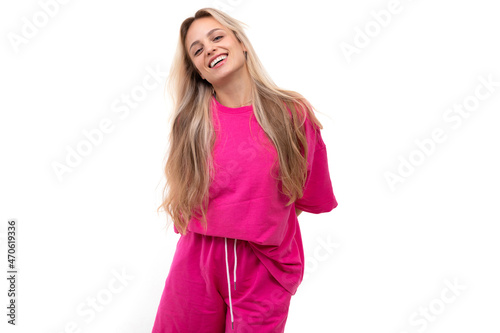 beautiful blonde in a light sports pink suit on a white background with a smile on her face