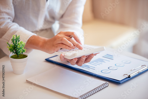 A young woman's hand presses a calculator to determine and summarize the cost of mortgage home loans for refinancing plans, lifestyle concepts.
