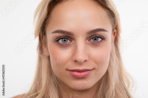 close-up portrait of a young blonde on a white background looking at the camera