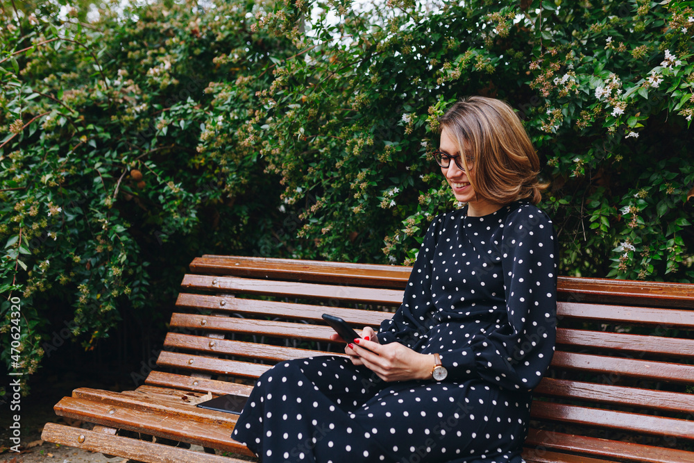 Smiling blond woman using mobile phone on bench Smiling blond woman using mobile phone on bench