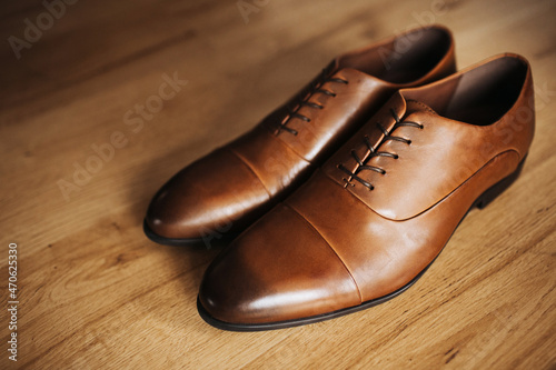 Brown leather shoe. Groom getting ready for the wedding. Wearing clothes background. Dressing up male fashion. Elegant shoes isolated on wooden floor. Wedding fashion clothing background.