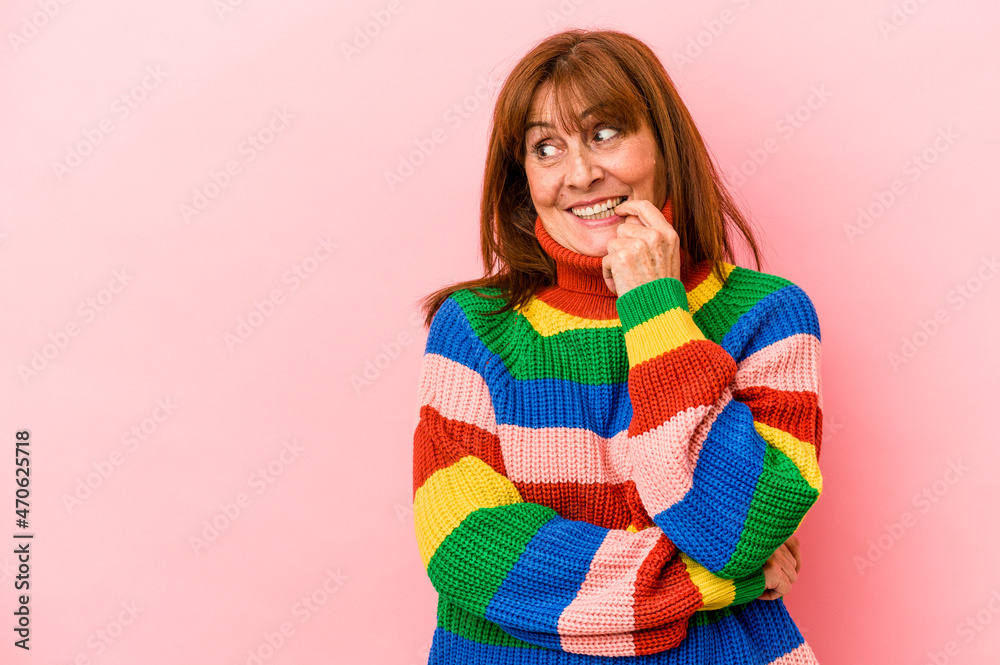Middle age caucasian woman wearing a multicolor sweater isolated on pink background relaxed thinking about something looking at a copy space. Middle age caucasian woman wearing a multicolor sweater isolated on pink background relaxed thinking about something looking at a copy space.