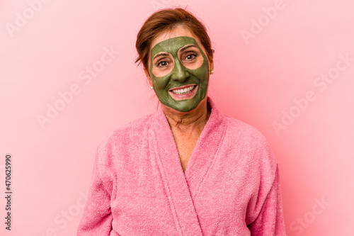 Middle age caucasian woman wearing a facial mask isolated on pink background happy, smiling and cheerful.