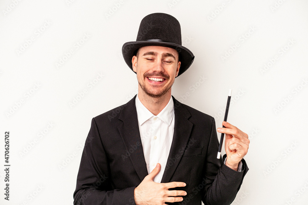 Young caucasian wizard man holding a wand isolated on white background laughing and having fun. Young caucasian wizard man holding a wand isolated on white background laughing and having fun.