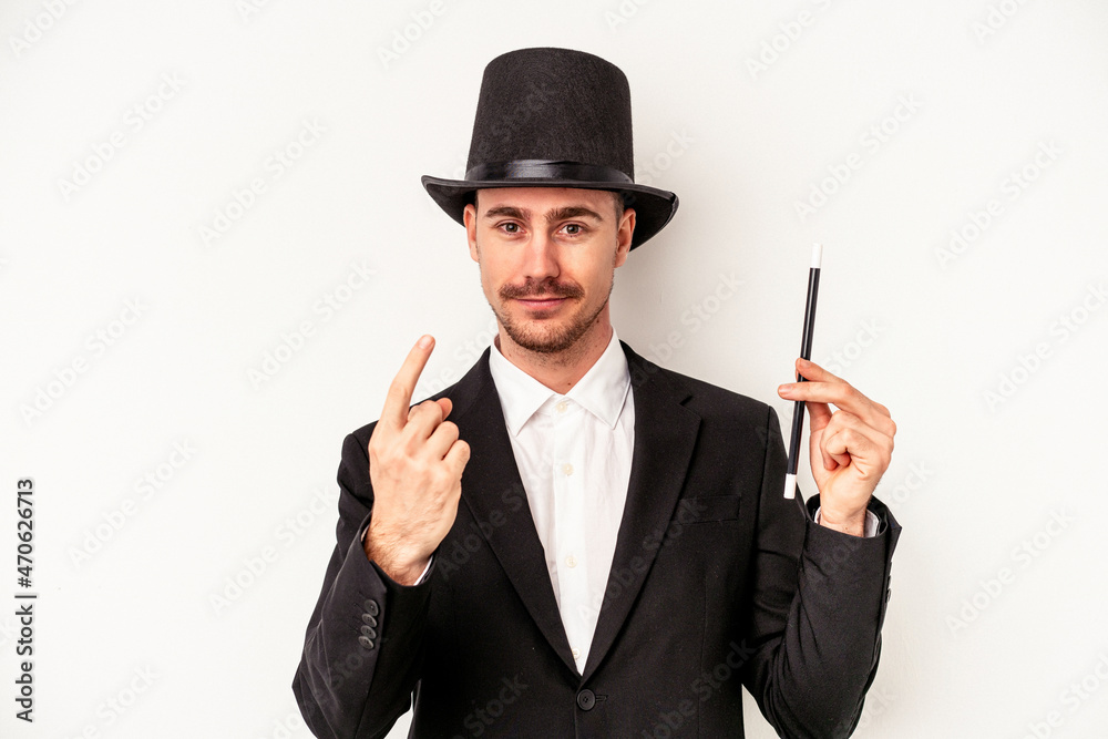 Young caucasian wizard man holding a wand isolated on white background pointing with finger at you as if inviting come closer. Young caucasian wizard man holding a wand isolated on white background pointing with finger at you as if inviting come closer.