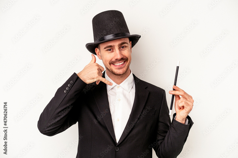 Young caucasian wizard man holding a wand isolated on white background showing a mobile phone call gesture with fingers. Young caucasian wizard man holding a wand isolated on white background showing a mobile phone call gesture with fingers.