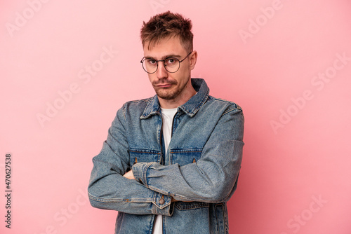 Young caucasian man isolated on pink background suspicious, uncertain, examining you. © Asier