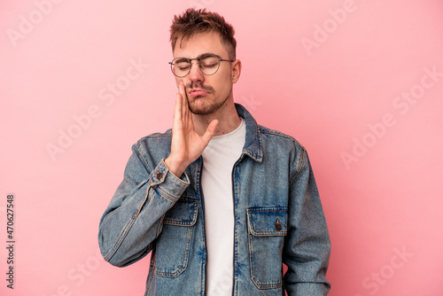 Young caucasian man isolated on pink background having a strong teeth pain, molar ache.