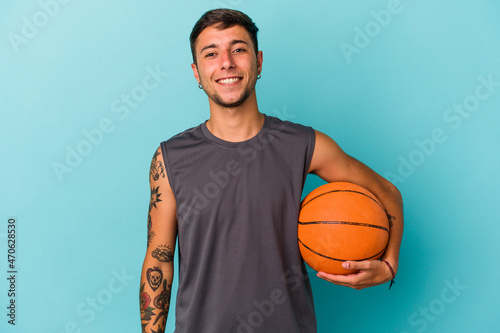 Young caucasian man playing basketball isolated on blue background happy, smiling and cheerful.