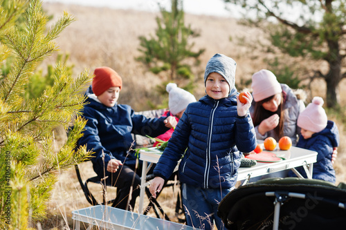 Cheerful mother with kids at a picnic. Family on vacation with fruits outdoor.