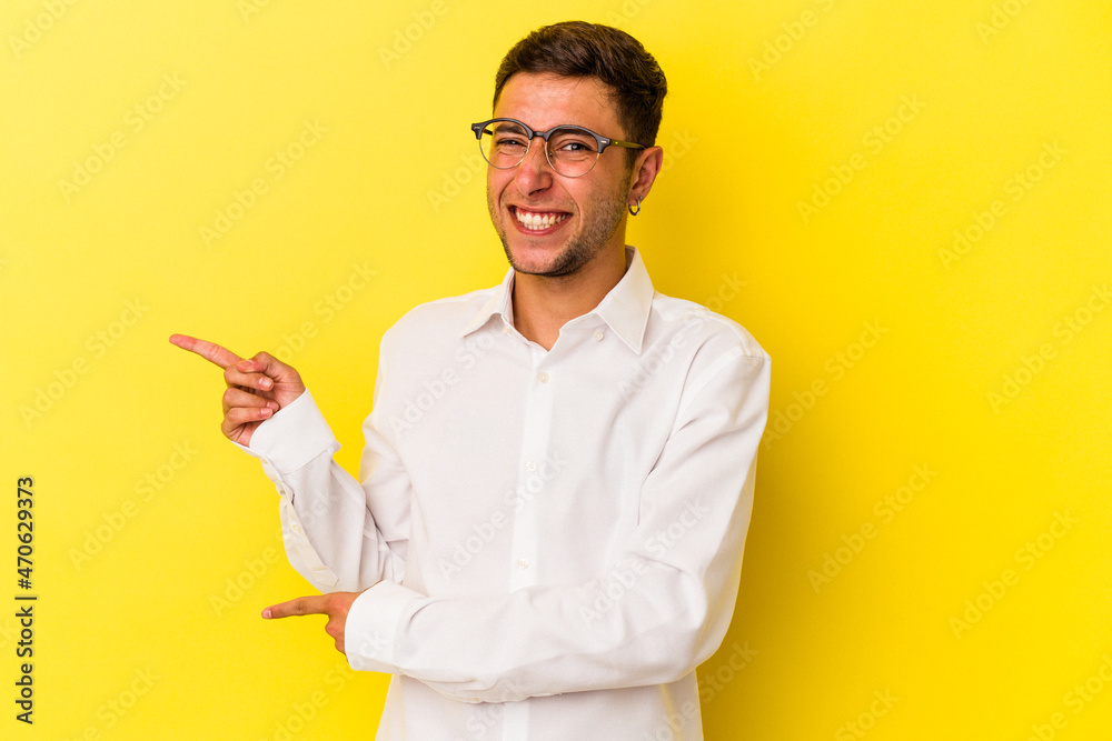 Young caucasian man with tattoos isolated on yellow background  shocked pointing with index fingers to a copy space.
