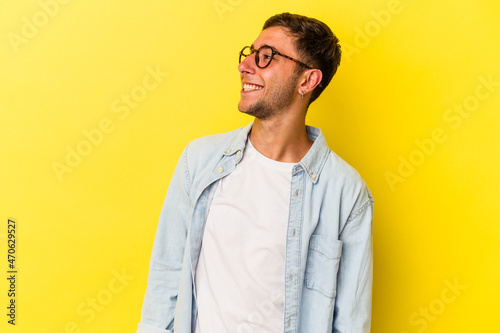 Young caucasian man with tattoos isolated on yellow background relaxed and happy laughing, neck stretched showing teeth.