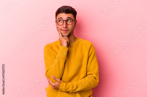 Young caucasian man with tattoos isolated on yellow background contemplating, planning a strategy, thinking about the way of a business.