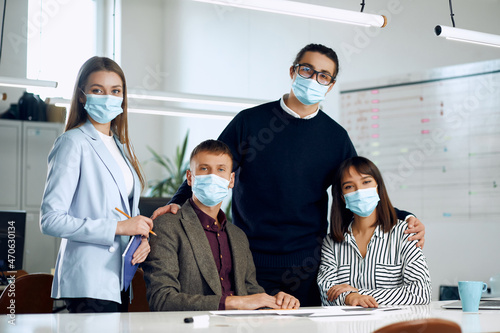 Team of office workers are looking at the camera while wearing masks.