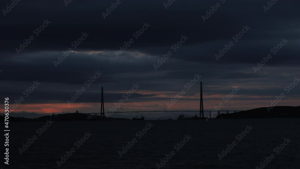 The sun rises against the background of the Russian bridge in Vladivostok in winter. Bright dawn against the background of the cable-stayed bridge across the Eastern Bosphorus. The sun rises against the background of the Russian bridge in Vladivostok in winter. Bright dawn against the background of the cable-stayed bridge across the Eastern Bosphorus.