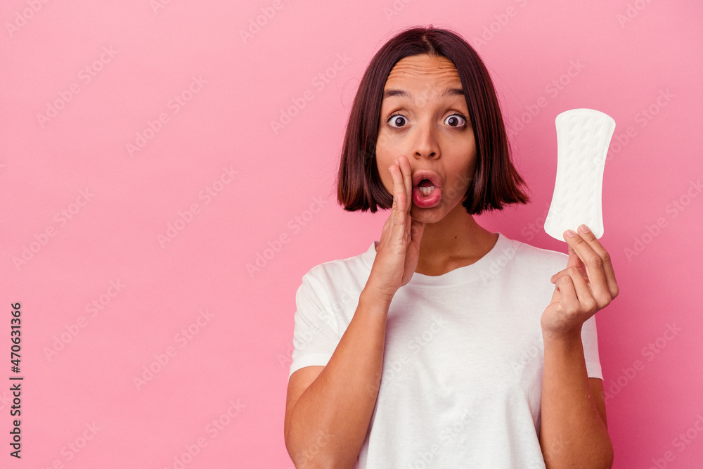 Young mixed race woman holding a compress isolated on pink background is saying a secret hot braking news and looking aside Young mixed race woman holding a compress isolated on pink background is saying a secret hot braking news and looking aside