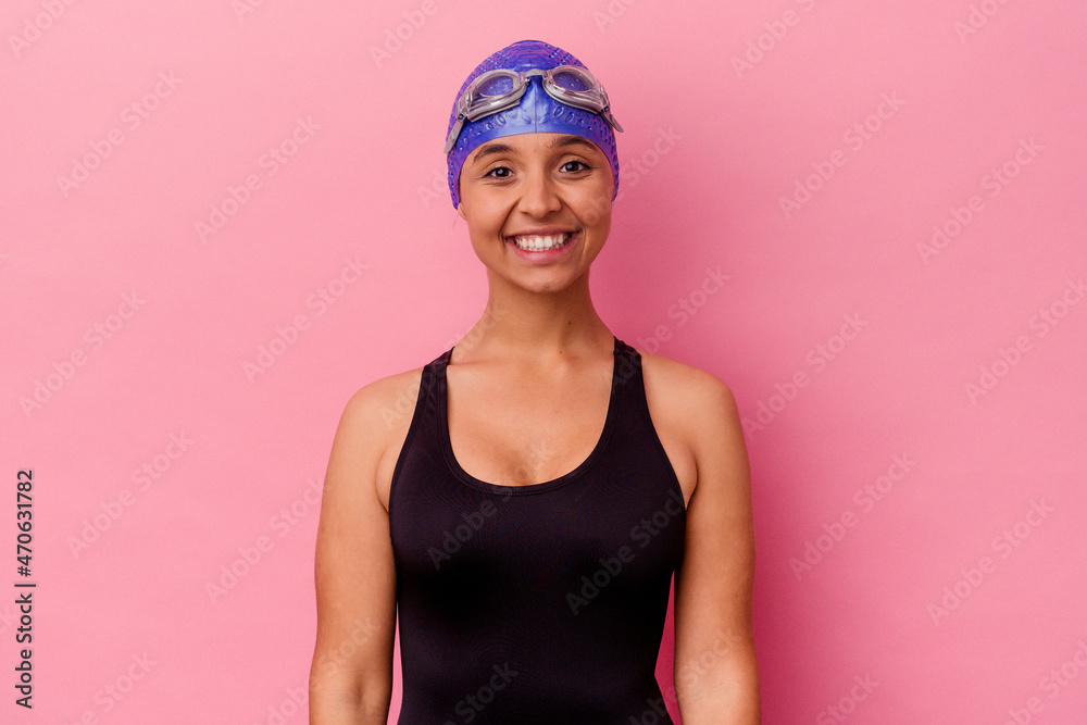 Young swimmer mixed race woman isolated on pink background happy, smiling and cheerful. Young swimmer mixed race woman isolated on pink background happy, smiling and cheerful.